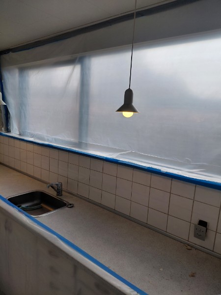 Vindue afskærmet med plast og tape under indvendigt asbest-arbejde